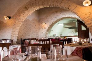 a restaurant with tables and chairs and a stone wall at Residenza Storica le Civette in Castel del Monte