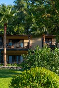a building with palm trees in front of it at Hotel Berke Ranch&Nature in Kemer