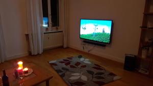 a living room with a television and a table with a candle at White House (1f) Boppard City in Boppard