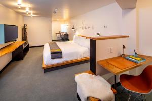 a hotel room with a bed and a desk and a tv at The FINCH in Walla Walla