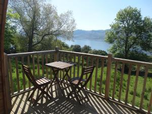 a table and chairs on a deck with a view of a lake at The Wee Lodge in Mallaig