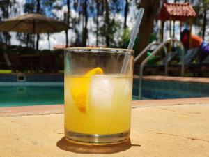a glass of orange juice sitting on a table near a swimming pool at Margarita House in Nairobi