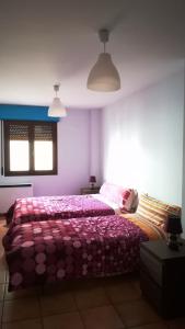 a bedroom with a bed with a pink comforter at Apartamento Martín in Mora de Rubielos