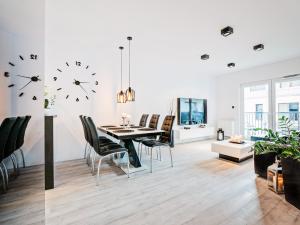 a dining room with a table and chairs and a clock on the wall at Apartamenty Homely Place 9 - Parking. in Poznań
