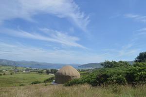 a yurt in a field with a lake in the background at Portsalon Luxury Camping in Portsalon