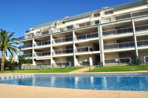 an apartment building with a swimming pool in front of it at Brisas C8, ático, 3 dormitorios, playa a 50m, by Bookindenia in Denia