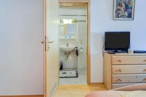 a bathroom with a shower with a sink and a television at Katharinenhof Wohnung Kramer (2) in Garmisch-Partenkirchen