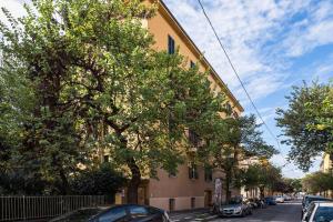 a tree next to a building with cars parked on the street at Residence Sant'Orsola - Pizzardi Suites Apartments in Bologna