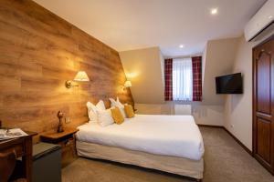 a hotel room with a large bed and a television at L'Abbaye d'Alspach in Kientzheim