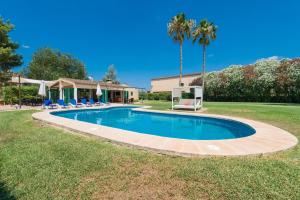 a swimming pool in a yard with chairs and a palm tree at VILLA CAN RITO in Felanitx