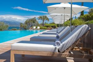 a row of lounge chairs with an umbrella and a pool at Casadelmar in Porto-Vecchio