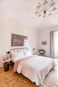een witte slaapkamer met een groot bed en een kroonluchter bij Casa di Artemisia in Rome