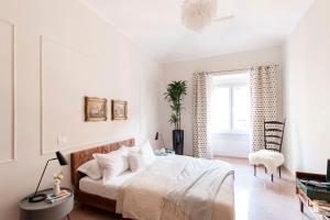een witte slaapkamer met een bed en een stoel bij Casa di Artemisia in Rome