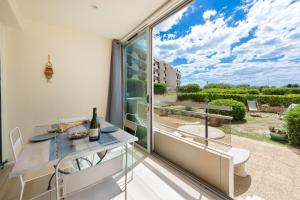 een eetkamer met uitzicht op een balkon bij La Comédie de Vanneau - L'Intermède in Palavas-les-Flots