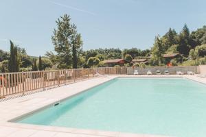 a swimming pool with chairs and a fence at Terres de France - Les Hameaux de Pomette in Marminiac