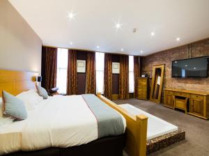 a bedroom with a large bed and a flat screen tv at OYO Imperial Hotel in Barrow in Furness