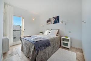 a white bedroom with a bed and a window at Via Alemania 16 Apartment in Port de Pollensa
