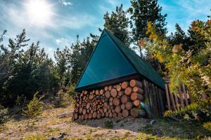 una pila de troncos con techo verde en La Quinta Glamping - Lago de Tota, en Cuítiva