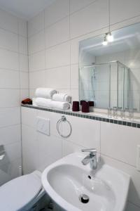 ein weißes Badezimmer mit einem Waschbecken und einem Spiegel in der Unterkunft Ricks City Hotel in Trier