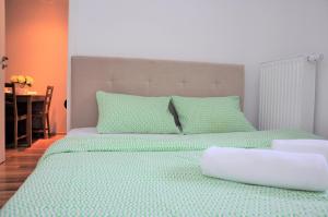 a bedroom with a bed with green sheets and a table at Prudentia Apartments Jana Kazimierza in Warsaw