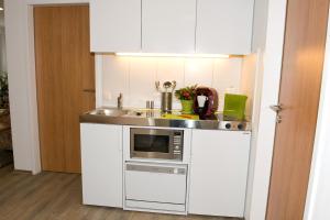 a white kitchen with a sink and a microwave at Ferienwohnungen - Boarding Wohnungen Sonnenhof in Lenzing