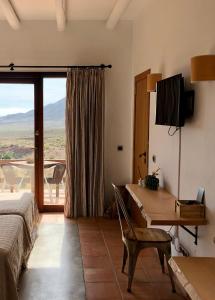 a bedroom with a bed and a desk and a window at Cortijo El Paraíso in Los Escullos