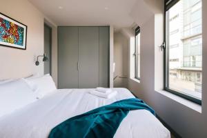 a white bed in a room with a window at The Interlock Apartments - Oxford St in London