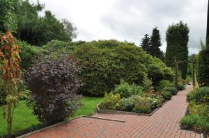 a garden with a brick path and bushes at Ferienwohnung Am Königsmoor, 65323 in Moormerland