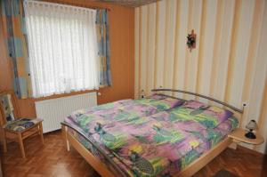 um quarto com uma cama com um edredão colorido em Ferienwohnung Am Königsmoor, 65323 em Moormerland