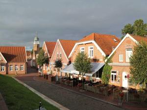 una fila de casas en un pueblo con una torre de reloj en Komfortable Ferienwohnung am Ditzumer Sieltief, 45019, en Jemgum