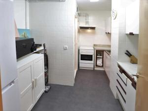 a kitchen with white tile walls and white appliances at Metropol apto per 5 pax primera linea mar d22223 in Sant Feliu de Guíxols