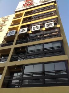 a tall yellow building with chinese signs on it at Matsumoto Ryokan in Kyoto