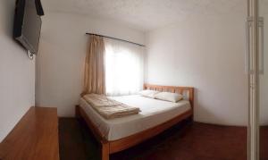 a small bedroom with a bed with a window at Tani Jiwo Hostel in Diyeng