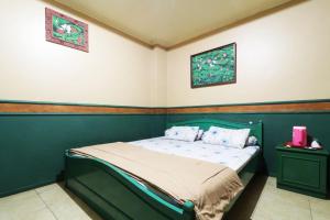 um quarto com uma cama verde e duas fotografias na parede em Hotel Alamanda em Jakarta