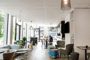 a restaurant with tables and chairs and a lobby at B&B HOTEL Zürich Wallisellen in Wallisellen