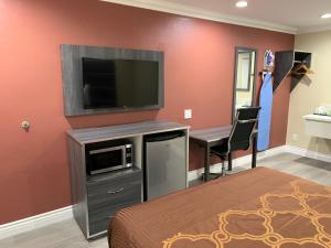 a bedroom with a bed and a flat screen tv at Pacific Inn Anaheim in Anaheim