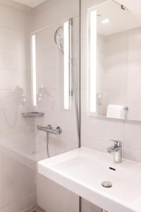 a white bathroom with a sink and a shower at B&B HOTEL Zürich Wallisellen in Wallisellen