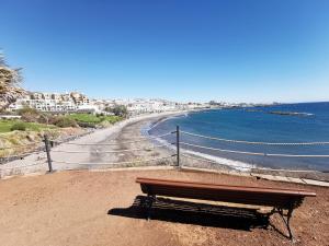 a bench sitting on the beach near the ocean at Home2Book Stunning Sea Views Adeje, Wifi & Pool in Playa Fañabe