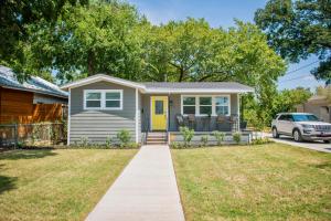 a small house with a yellow door and a driveway at Walk to the Silos! 3 Bed 1960's Bungalow near Baylor in Waco