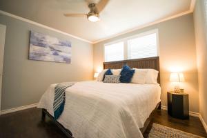 a bedroom with a bed with blue pillows and a window at Walk to the Silos! 3 Bed 1960's Bungalow near Baylor in Waco