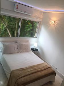 a small bedroom with a bed and a window at Apart Hotel Delphin Guaruja in Guarujá