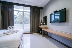 Habitación de hotel con cama, escritorio y TV. en Jintana Resort, en Buriram