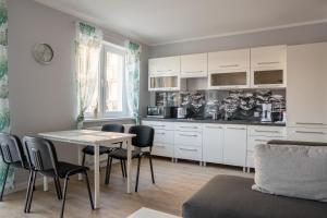 a kitchen with white cabinets and a table and chairs at Apartment Ella in Świnoujście