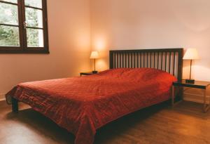 1 dormitorio con 1 cama roja, 2 mesas y 2 lámparas en Terres de France - Moncontour Active Park, en Moncontour-de-Poitou
