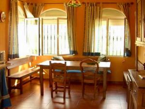 Un comedor con mesa y sillas y ventanas. en Casa Cantarrana, en Arriate