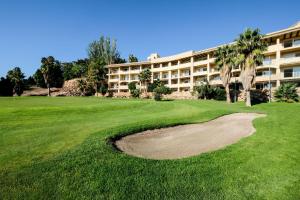 un campo de golf con un edificio en el fondo en Envía Almería Apartments Spa & Golf en Aguadulce