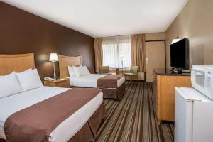 a hotel room with two beds and a flat screen tv at Travelodge by Wyndham Deltona in Deltona