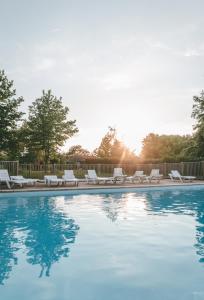 una piscina con tumbonas blancas y sol en Terres de France - Natura Resort Pescalis, en Moncoutant