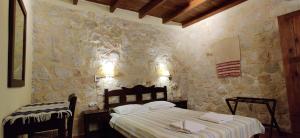 a bedroom with a bed and a stone wall at Ville du Soleil - exclusive homes with rustic charm and sensational views of the Mediterranean Sea in Makry Gialos
