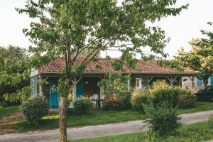 una casa con un árbol delante de ella en Terres de France - Natura Resort Pescalis, en Moncoutant